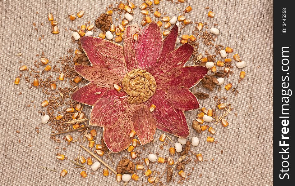 flower made of painted corn leafs and mixed cereals on flax background - autumn bounty and diversity