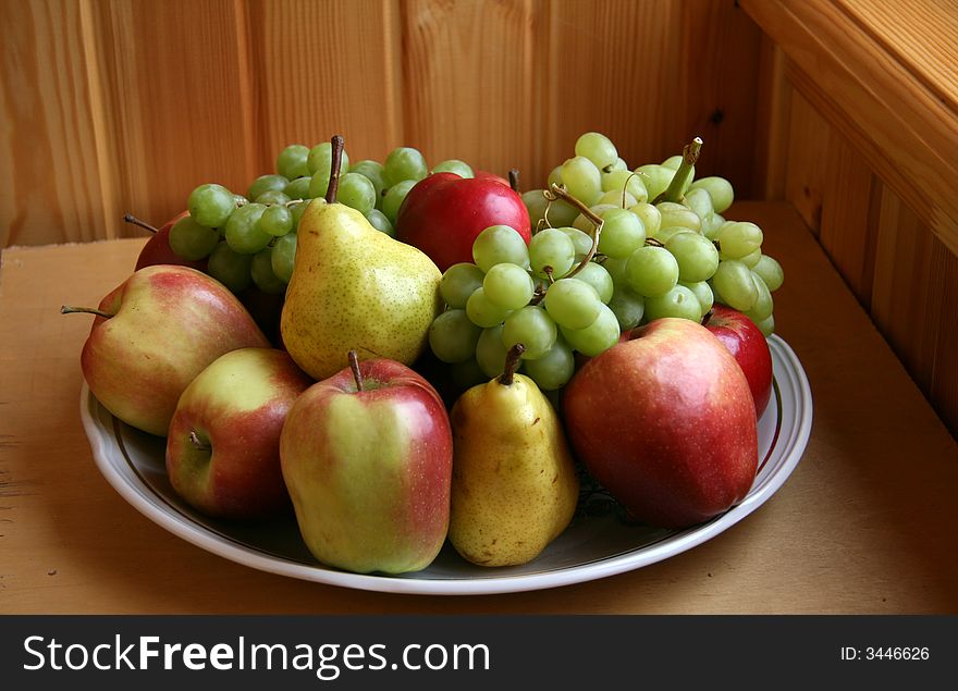 Still-life from fruit on a dish on a wooden table