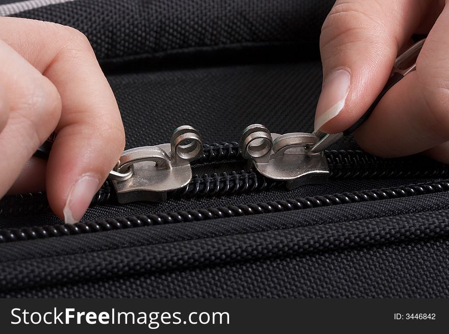 Hands opening the zipper of a black travel bag. Hands opening the zipper of a black travel bag