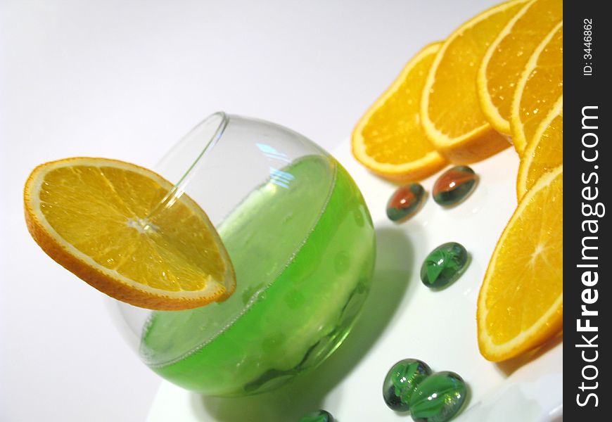 Sphere glass with bright green shower gel inside on white plate with fresh juicy oranges. Sphere glass with bright green shower gel inside on white plate with fresh juicy oranges