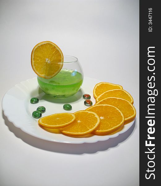 Sphere glass with bright green shower gel inside on white plate with fresh juicy oranges. Sphere glass with bright green shower gel inside on white plate with fresh juicy oranges