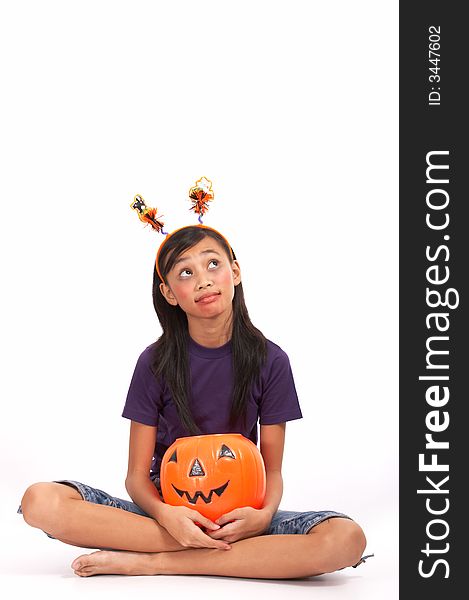 A young girl looking up while holding a pumpkin. A young girl looking up while holding a pumpkin