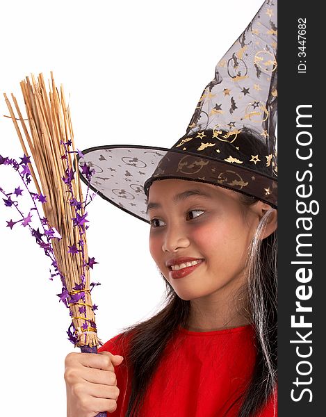 A young girl dressed in a witch costume looking at her broomstick