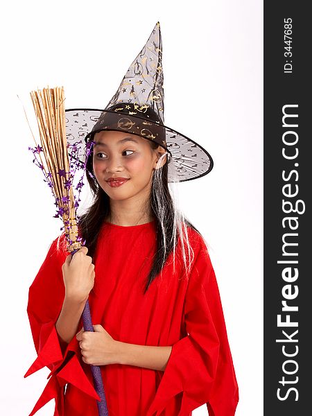 A young girl dressed in a witch costume looking at her broomstick