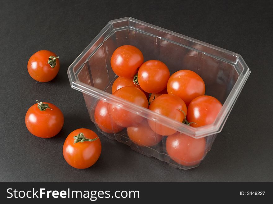 Cherry tomatoes in plastic container over black background. Cherry tomatoes in plastic container over black background