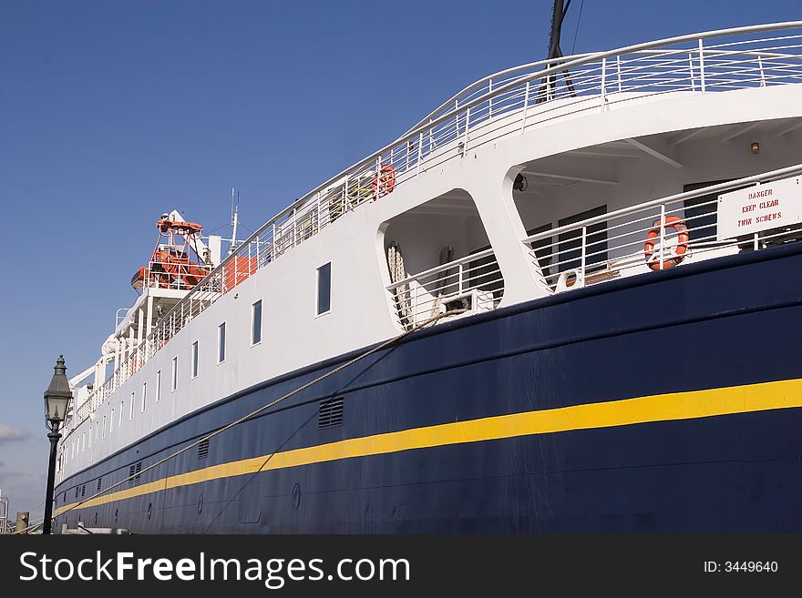 A small blue and yellow passenger ship. A small blue and yellow passenger ship