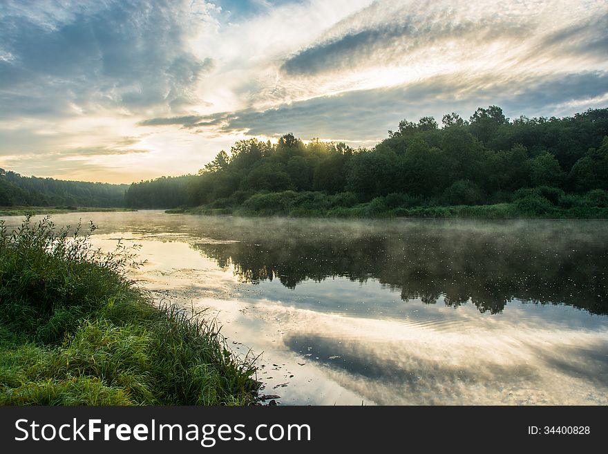 Dawn on the river Volga. Beautiful clouds and mist over the river, a reflection of the clouds and forests in water. Dawn on the river Volga. Beautiful clouds and mist over the river, a reflection of the clouds and forests in water.