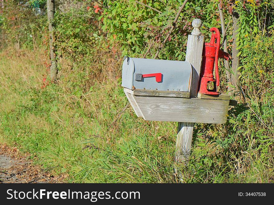 Classic country mailbox with repurposed vintage water pump for decoration.