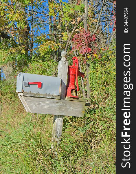 Classic country mailbox with repurposed vintage water pump for decoration.