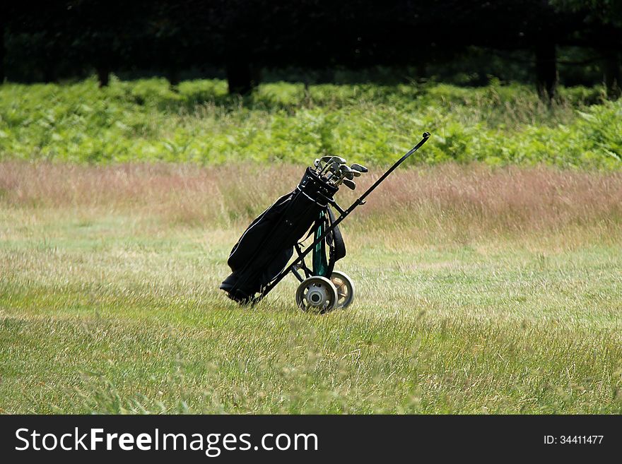 A Single Golf Trolley Standing at the end of a Fairway. A Single Golf Trolley Standing at the end of a Fairway.