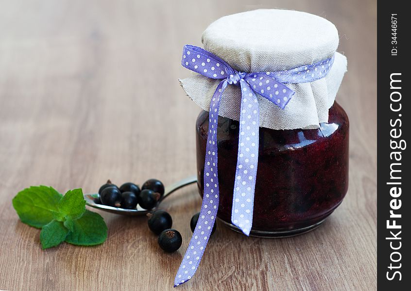 Black currants jam on a old wooden background