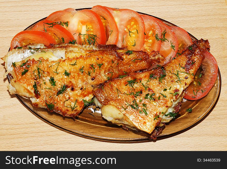 Roasted sea fish with tomato and dill on a glass platter. Roasted sea fish with tomato and dill on a glass platter