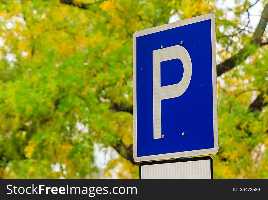 Element of the urban landscape. road sign - parking on a background of yellow foliage in the park. Element of the urban landscape. road sign - parking on a background of yellow foliage in the park