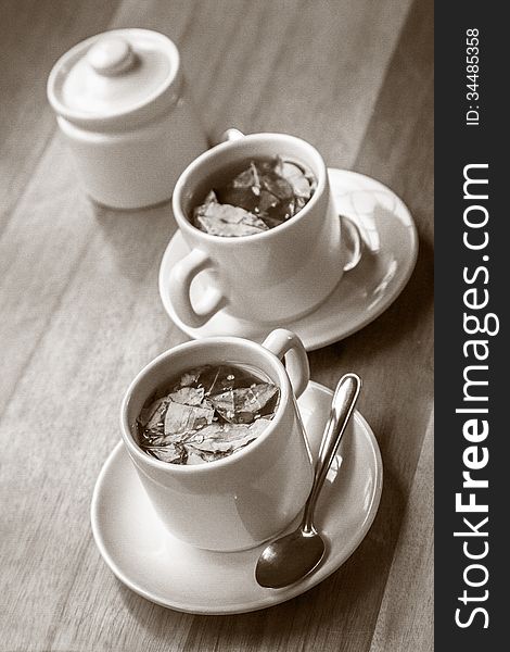 Cups of Coca Tea on Wooden Table with Diagonal Lines. Coca tea made from raw coca leaves.