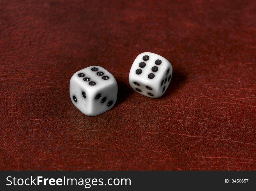 Two dices lying on red leather and showing a six
