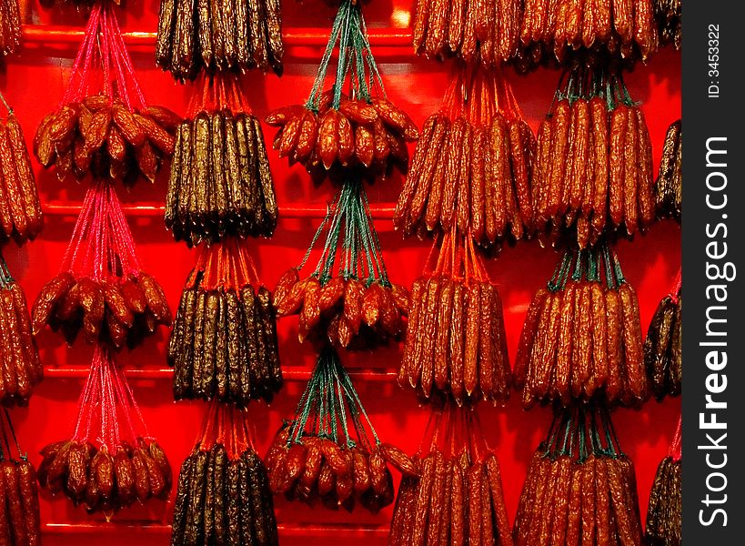Various types of Chinese sausages hung for sale on red poles against a red background illuminated by yellow light, on sale prior to the Chinese New Year in Chinatown. Various types of Chinese sausages hung for sale on red poles against a red background illuminated by yellow light, on sale prior to the Chinese New Year in Chinatown.