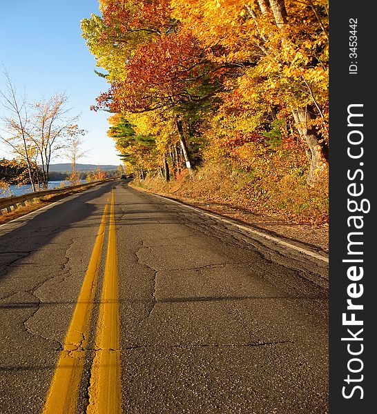 Along a rural two lane road in Maine, an Autumn view with red and yellow maple trees. Along a rural two lane road in Maine, an Autumn view with red and yellow maple trees
