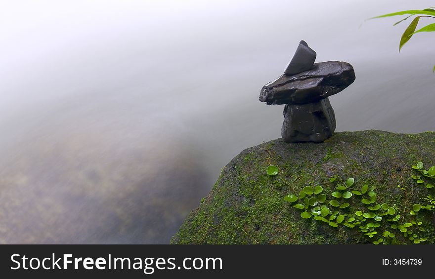 Stones arrangement on rock surface captured against natural stream of waterfall. Stones arrangement on rock surface captured against natural stream of waterfall.