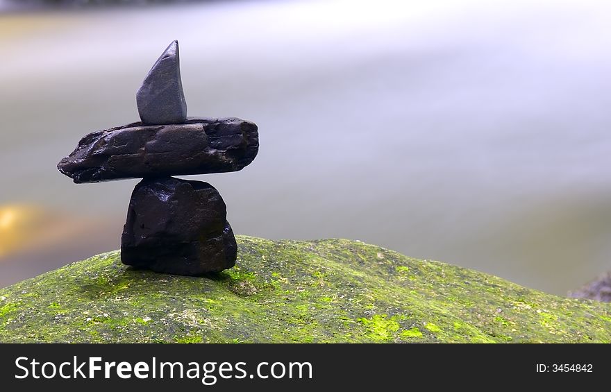 Stones arrangement on rock surface captured against natural stream of waterfall. Stones arrangement on rock surface captured against natural stream of waterfall.