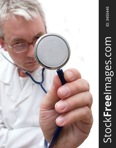 Pensive doctor in glasses listening the stethoscope. Soft-focused, focal point is on the stethoscope. Pensive doctor in glasses listening the stethoscope. Soft-focused, focal point is on the stethoscope