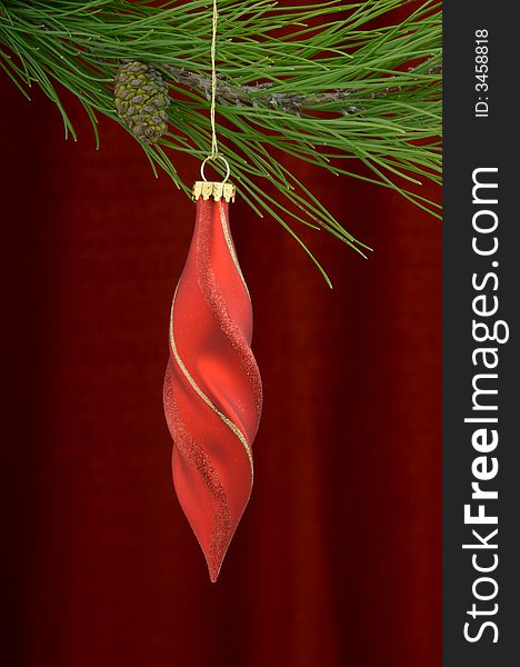 Christmas tree ornament with a pine tree branch in the top of the image, a red decoration being the main focus. Christmas tree ornament with a pine tree branch in the top of the image, a red decoration being the main focus