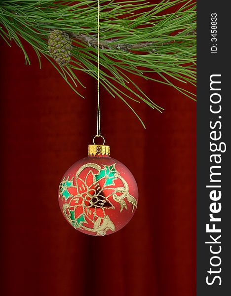 Christmas tree ornament with a pine tree branch in the top of the image, a red,gold and green holly decoration being the main focus. Christmas tree ornament with a pine tree branch in the top of the image, a red,gold and green holly decoration being the main focus