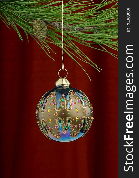 Christmas tree ornament with a pine tree branch in the top of the image, a blue hand painted decoration being the main focus. Christmas tree ornament with a pine tree branch in the top of the image, a blue hand painted decoration being the main focus