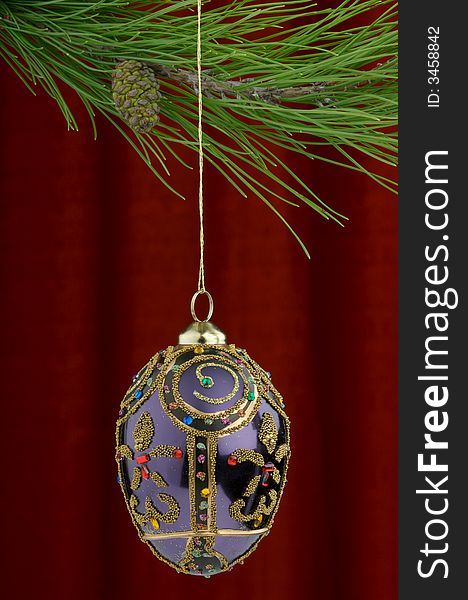 Christmas tree ornament with a pine tree branch in the top of the image, a purple hand painted decoration being the main focus. Christmas tree ornament with a pine tree branch in the top of the image, a purple hand painted decoration being the main focus