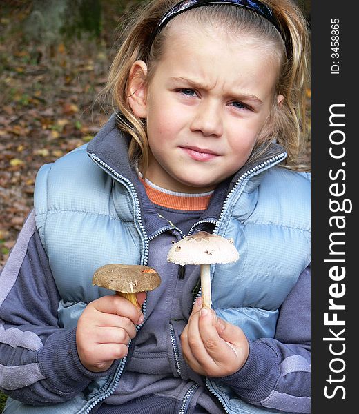 Small boy with mushrooms in the forest