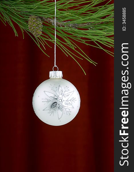 An image of a white and silver Christmas ornament on a burgundy background. An image of a white and silver Christmas ornament on a burgundy background