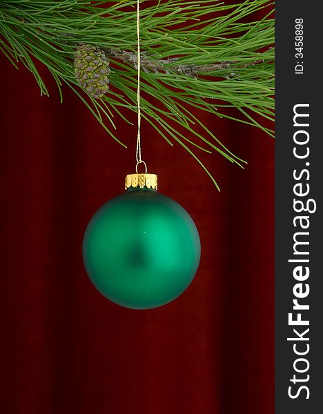 An image of a green Christmas ornament on a burgundy background. An image of a green Christmas ornament on a burgundy background