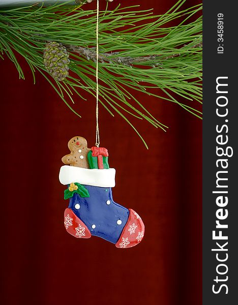 An image of a stocking Christmas ornament on a burgundy background. An image of a stocking Christmas ornament on a burgundy background