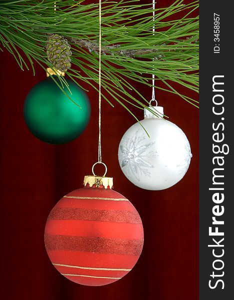 An image of multicolored Christmas ornaments on a burgundy background. An image of multicolored Christmas ornaments on a burgundy background