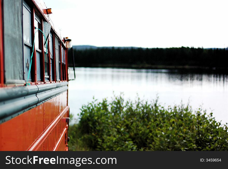 An old abandoned bus sits on the bank of a river. An old abandoned bus sits on the bank of a river