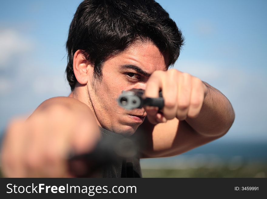 A young, robust man, in his 20's with dark hair pointing 2 pistols to the camera. A young, robust man, in his 20's with dark hair pointing 2 pistols to the camera.