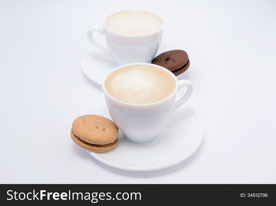 Coffee with milk and cream in beautiful fine china rates and chocolate and vanilla cookies filled. Coffee with milk and cream in beautiful fine china rates and chocolate and vanilla cookies filled