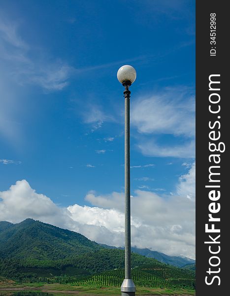 Blue sky and mountain background with luminaire pole on a good weather. Blue sky and mountain background with luminaire pole on a good weather