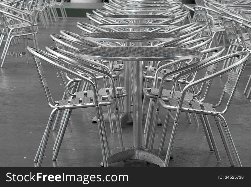 Row of empty silver tables and silver chairs outside a restaurant. Row of empty silver tables and silver chairs outside a restaurant