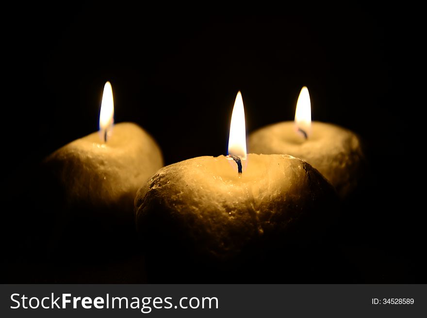 Photo of three candles isolated on the black background.