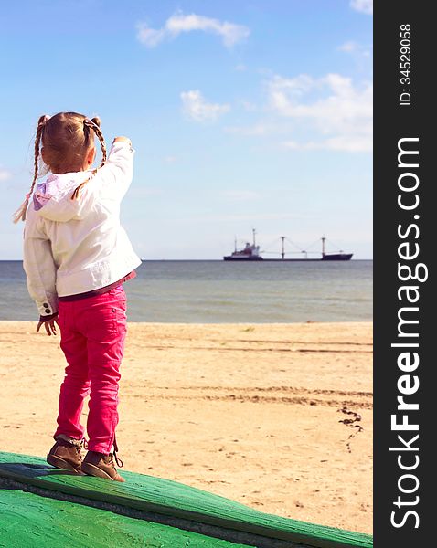 Girl on the beach showing to the ship in the sea. Girl on the beach showing to the ship in the sea.