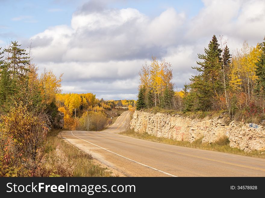 Winding Highway Between A Rock Ridge And Trees