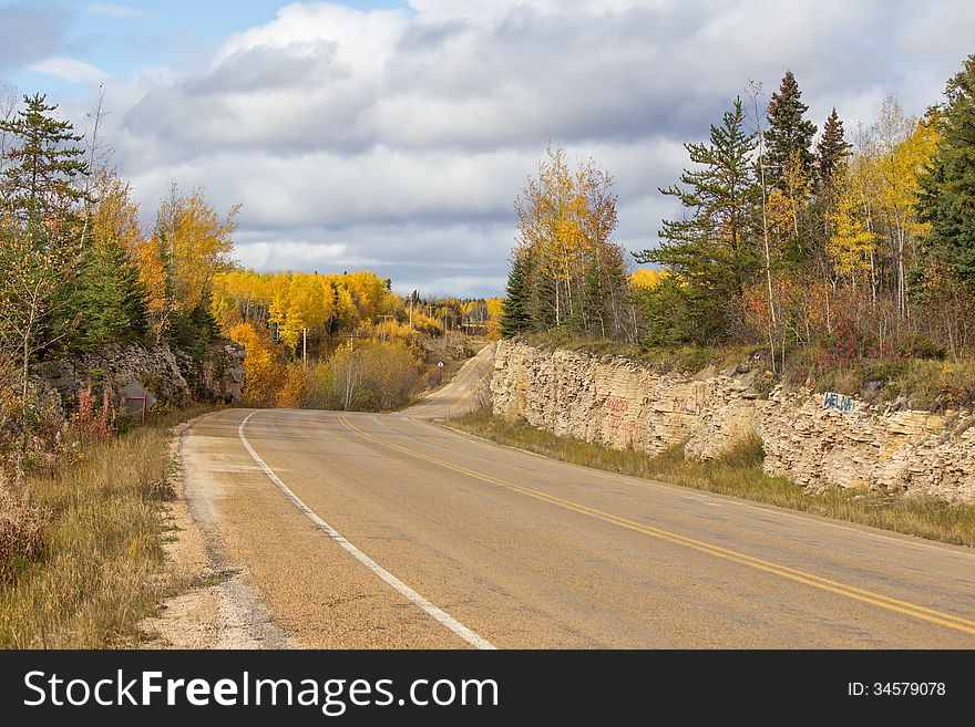 Winding Highway Between A Rock Ridge And Trees