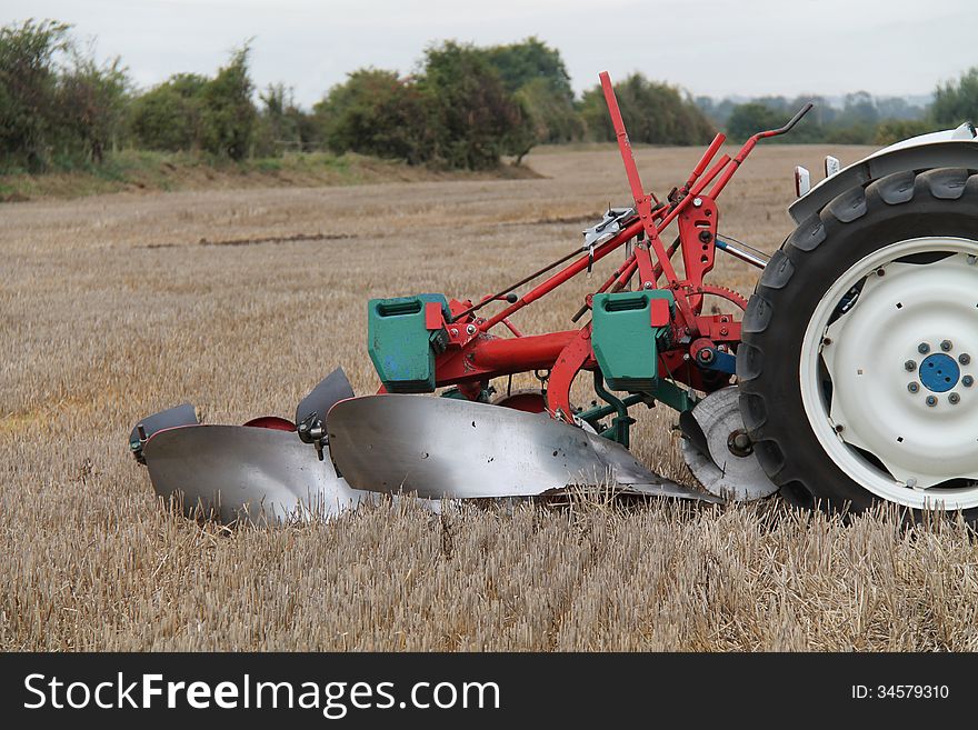 A Vintage Farming Plough Pulled by an Old Tractor. A Vintage Farming Plough Pulled by an Old Tractor.