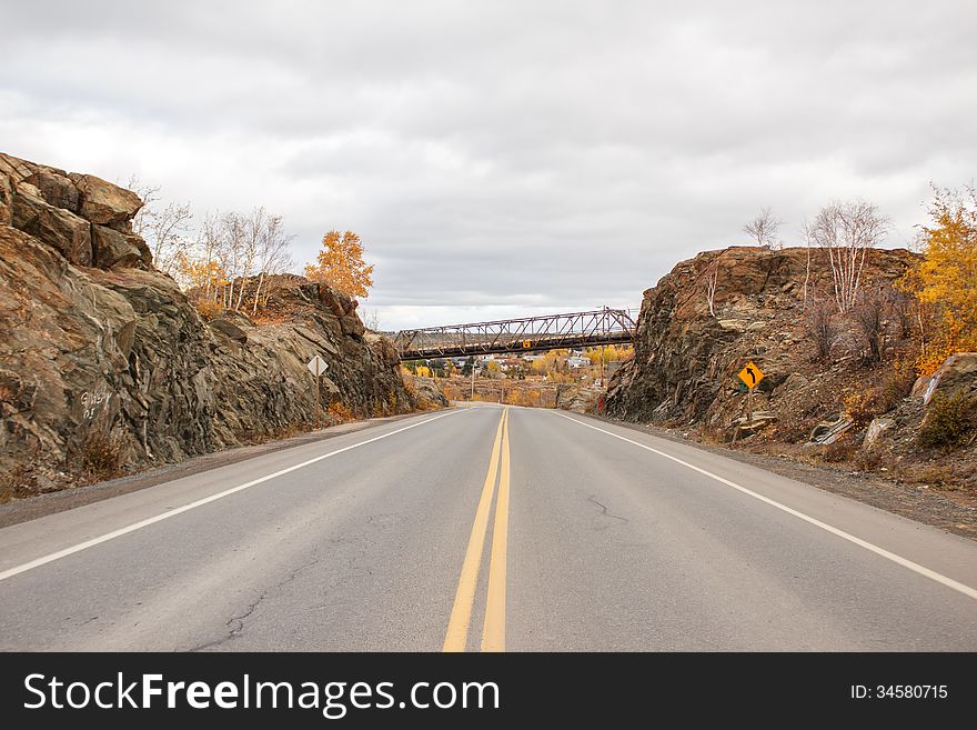 A Highway Between A Rock Ridge With A Bridge Overhead