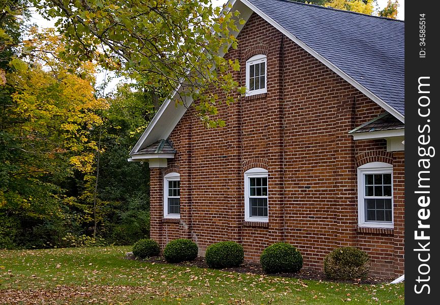 Brick architecture with windows that have white trim in a fall setting. Brick architecture with windows that have white trim in a fall setting.