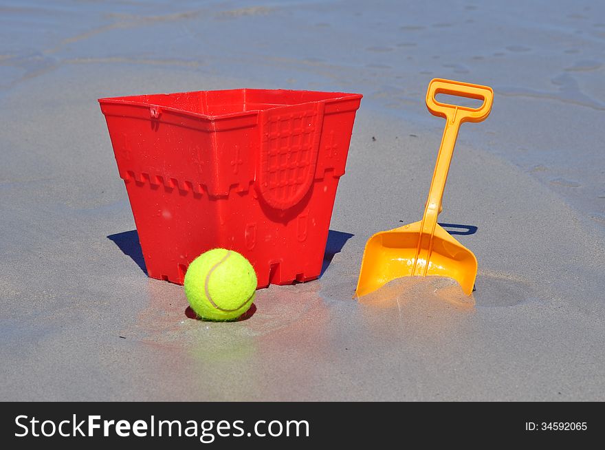 Red bucket spade and ball on the beach