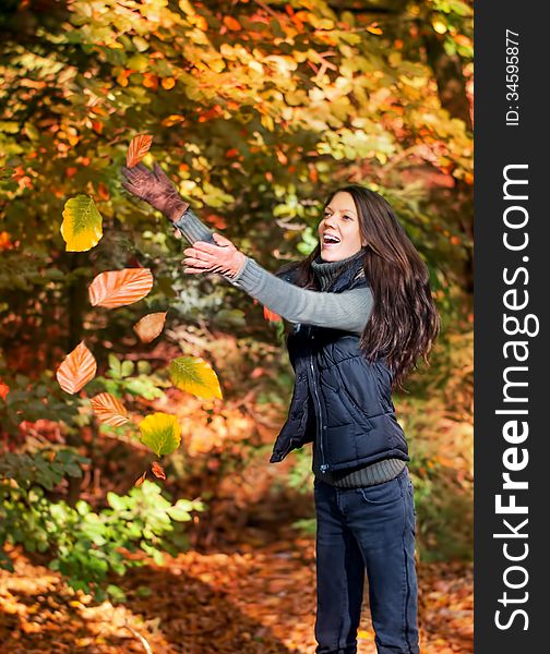 Woman catching leaves in autumnal forest