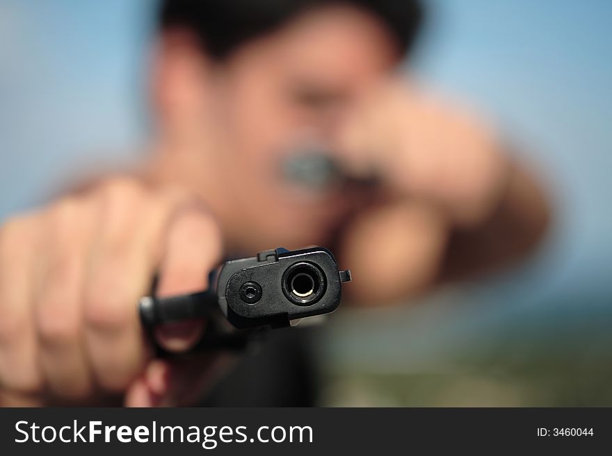 A young, robust man, in his 20's with dark hair pointing 2 pistols to the camera. A young, robust man, in his 20's with dark hair pointing 2 pistols to the camera.