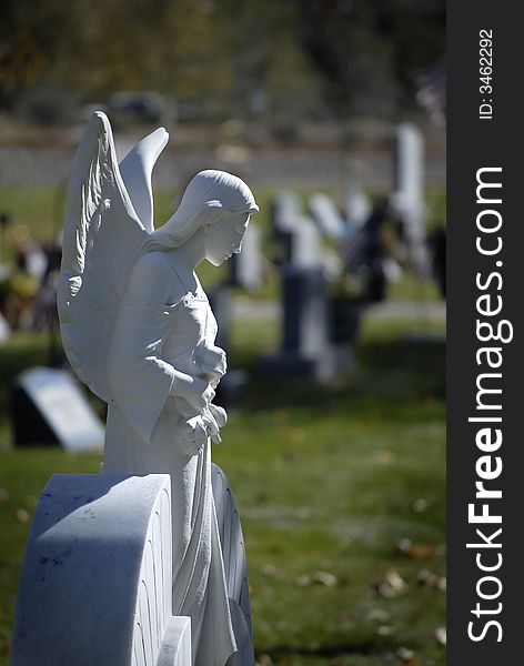 White marble statue of a winged angel in grave yard cemetery. White marble statue of a winged angel in grave yard cemetery