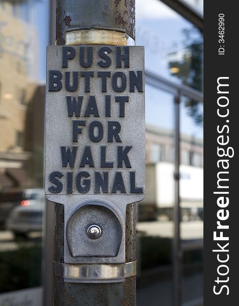 Crosswalk button on pole at intersection with sign